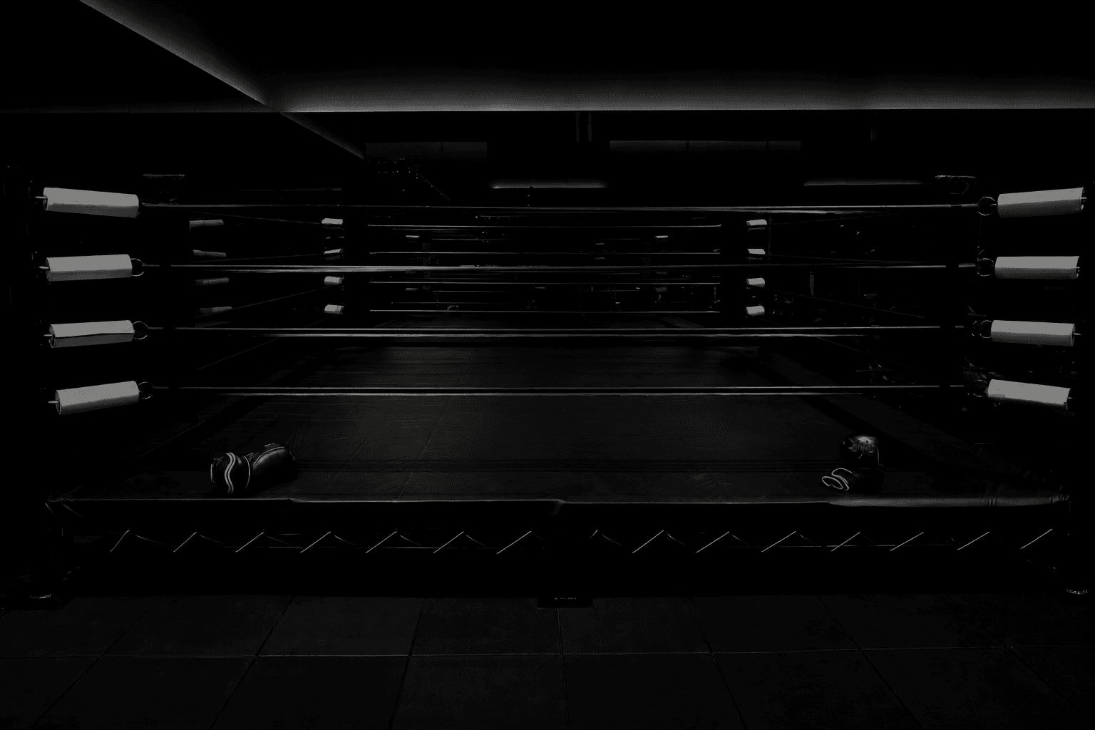 Loş ışıklı spor salonundaki siyah boks ringi.